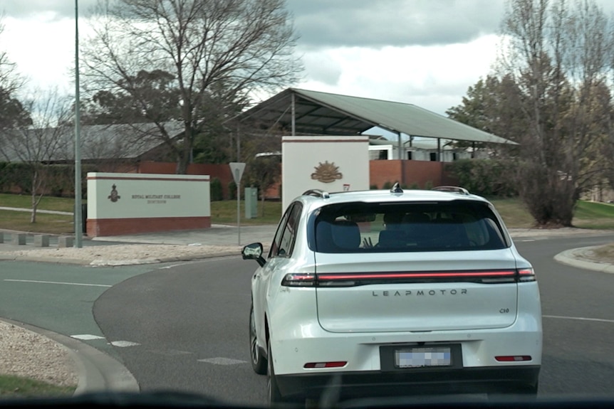 A white Leapmotor car enters a roundabout. In front of it are signs showing the Australian military emblem and 'Duntroon'