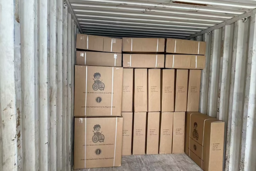 Cardboard boxes, with Kids on Wheels written on them, are stacked on top of each other.