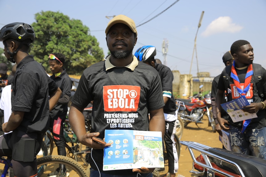 People wearing shirts that say 'stop ebola' holding information pamphlets. 