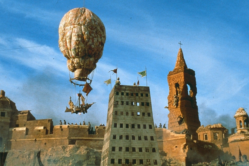 A hot air balloon floats over a Middle Eastern fortress