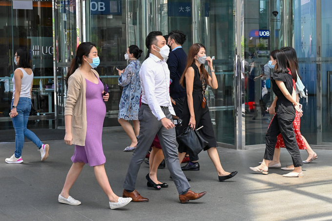 Office workers walk out for a lunch break at Raffles Place financial business district in Singapore on May 10, 2022. Photo by AFP