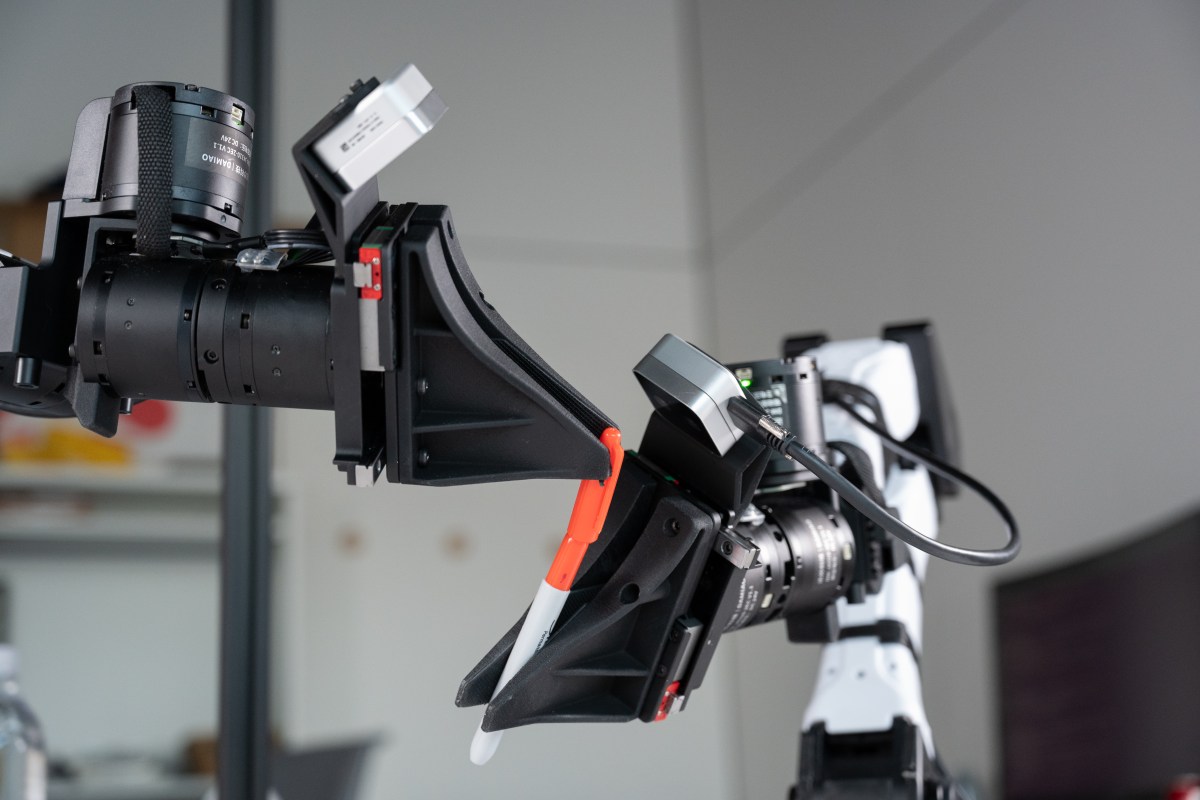 XDOF's robotic arms manipulate a pen and cap.