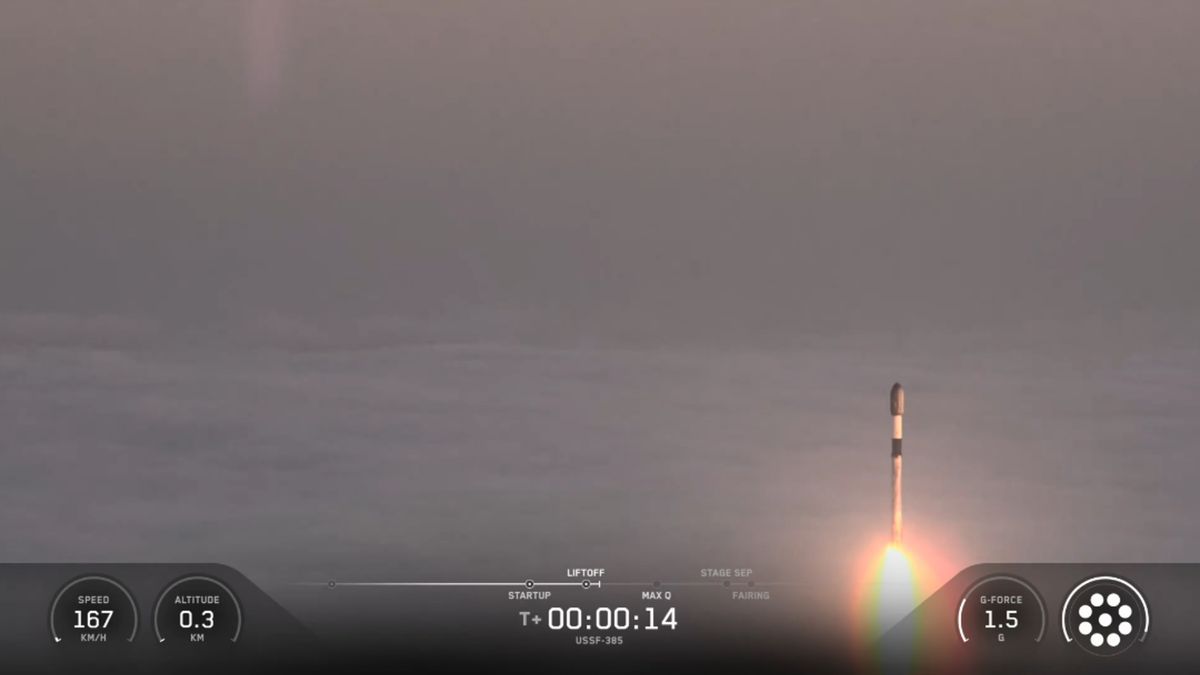 A SpaceX rocket rises out of the clouds and fog during a classified launch to space.
