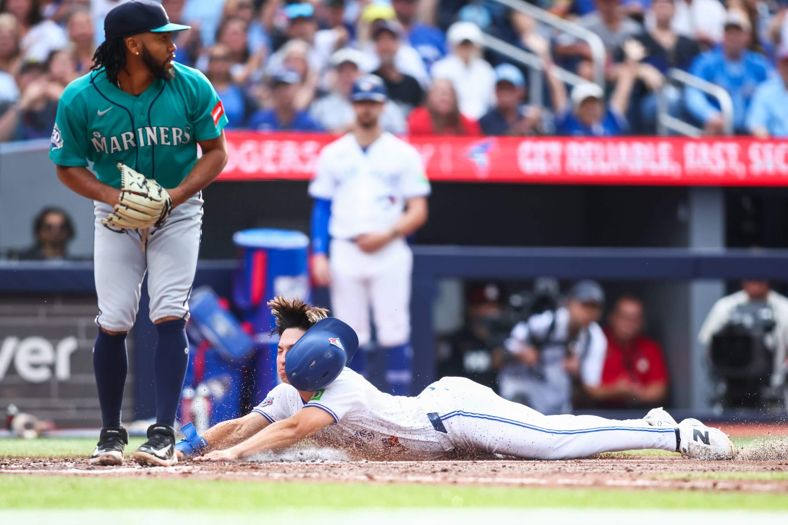 Brett Bateman of the Toronto Blue Jays, with his helmet askew, slides home to score on a wild pitch against the Seattle Mariners.