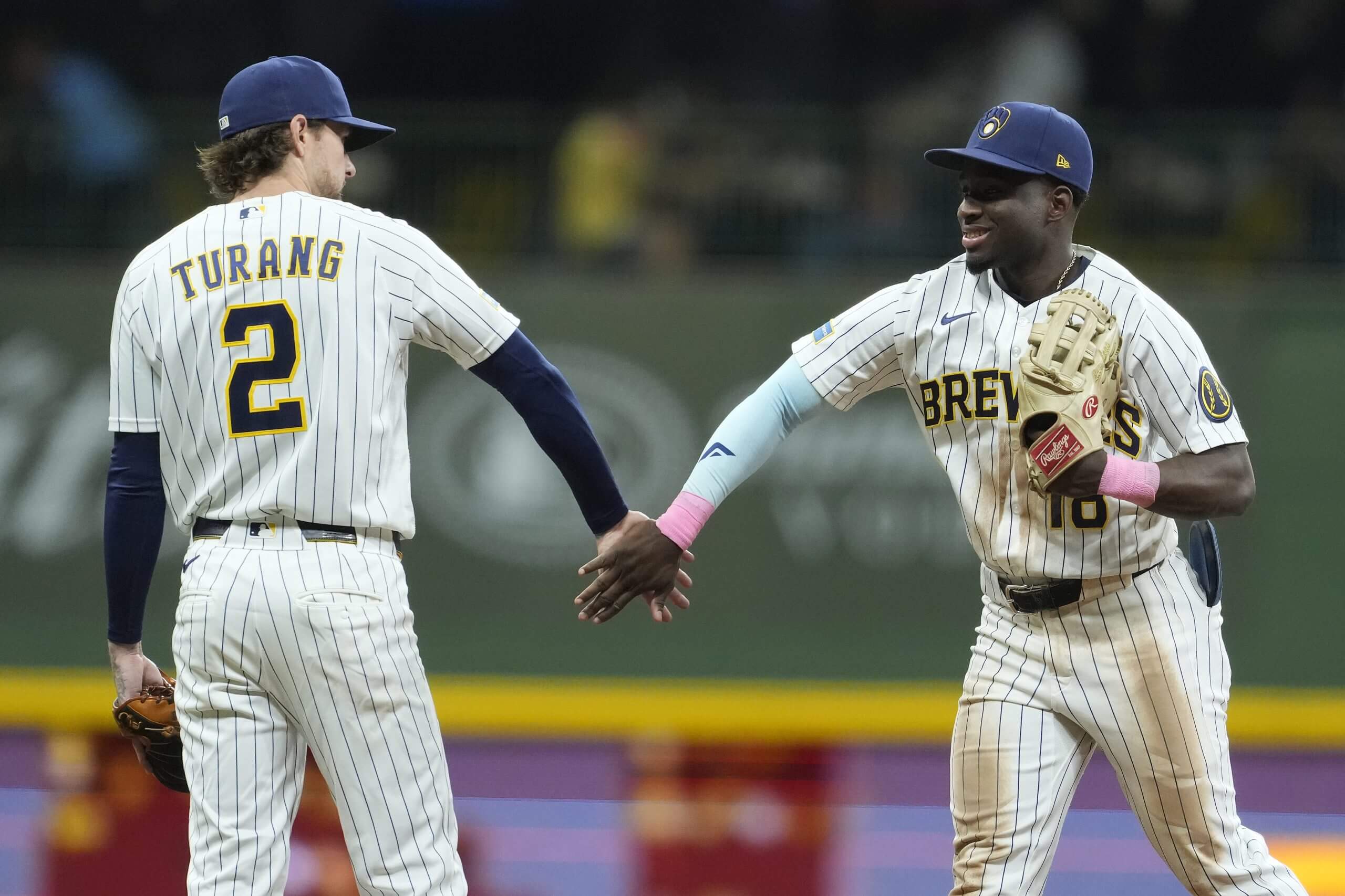 Brice Turang and Luis Lara slap hands on the diamond after defeating the Texas Rangers on Saturday. (Patrick McDermott / Getty Images)