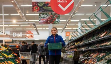Female Tesco employee holding produce crate