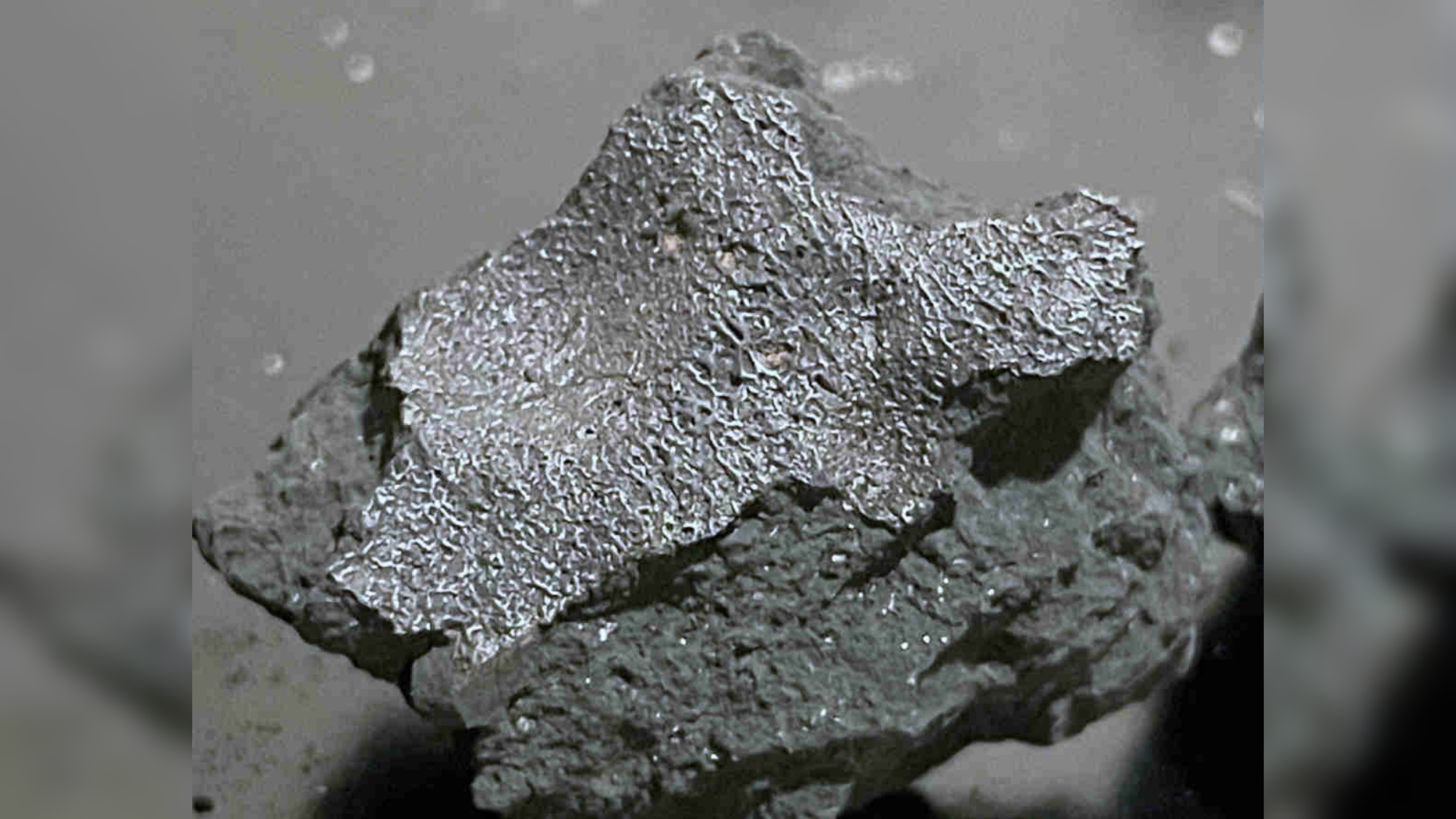 a lumpy black rock in a glass case