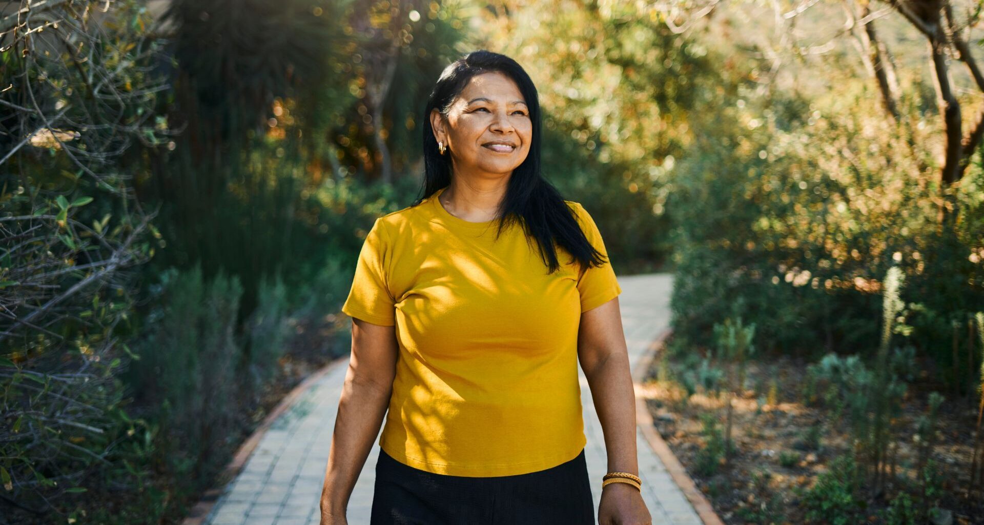 Woman walking along path in sunshine