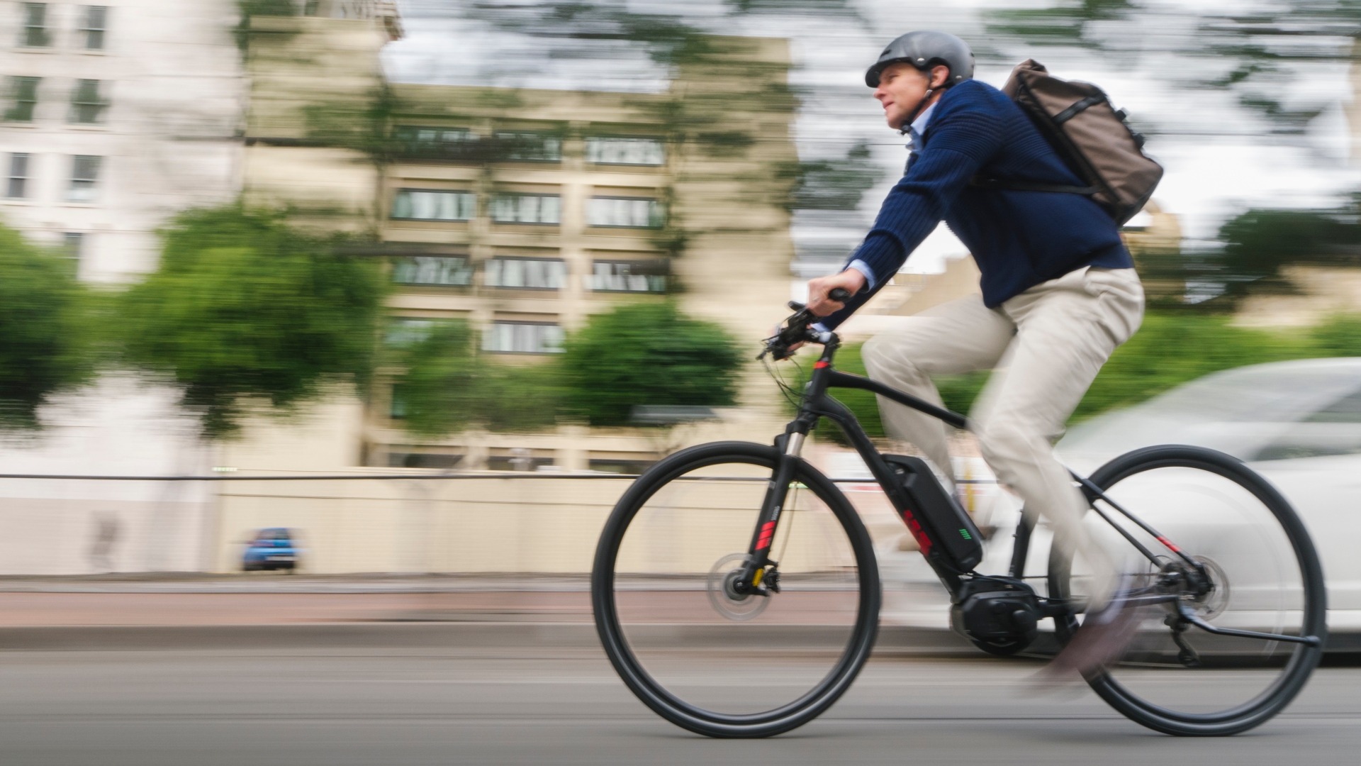 a man commutes to work on his electric battery powered ebike wearing casual business clothing and a helmet