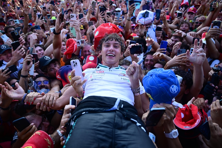F1 driver Kimi Antonelli crowd surfing with fans after winning a race