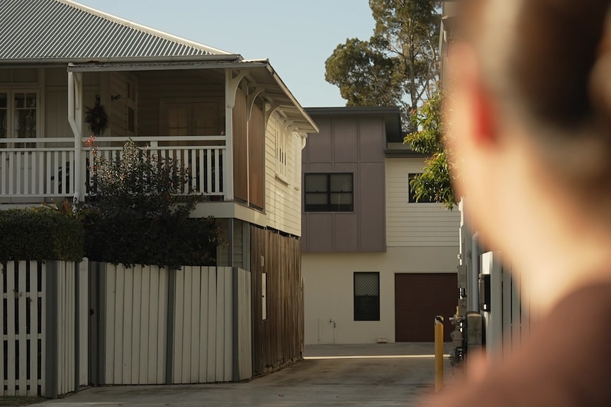 woman with a bun looks at a house