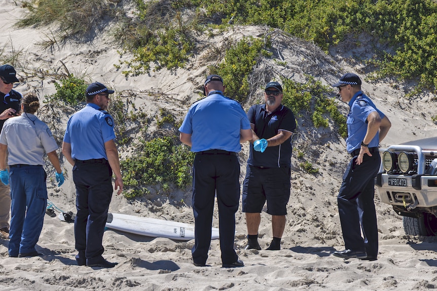 A group of uniformed officials stand around a surf board