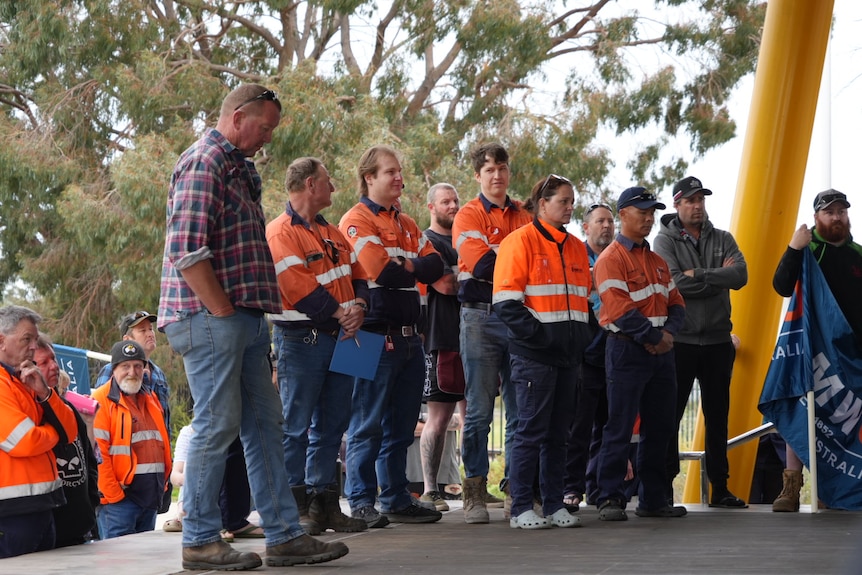 Men and a woman, most in high-vis, stand on an outdoor platform.
