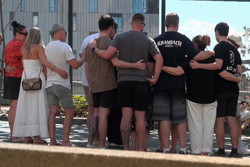 a group of people all hugging each other at the site where a young police officer died in a crash