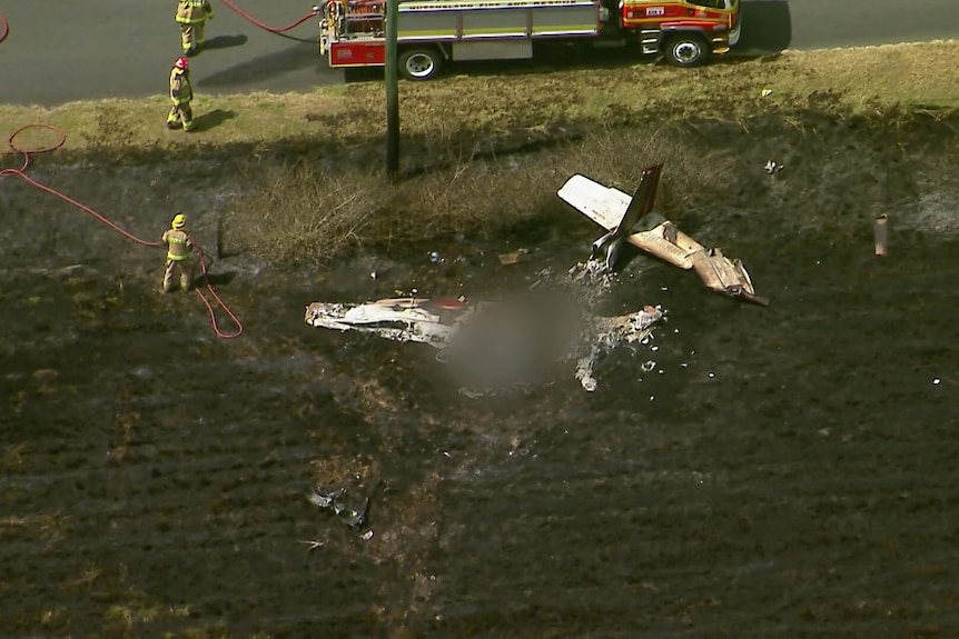 firefighters work to put out a fire after a plane crash in a field