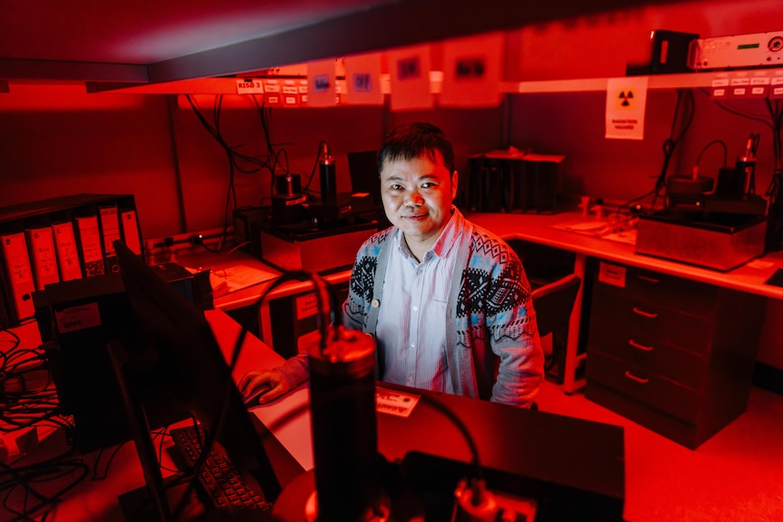 Scientist in lab bathed in red light.