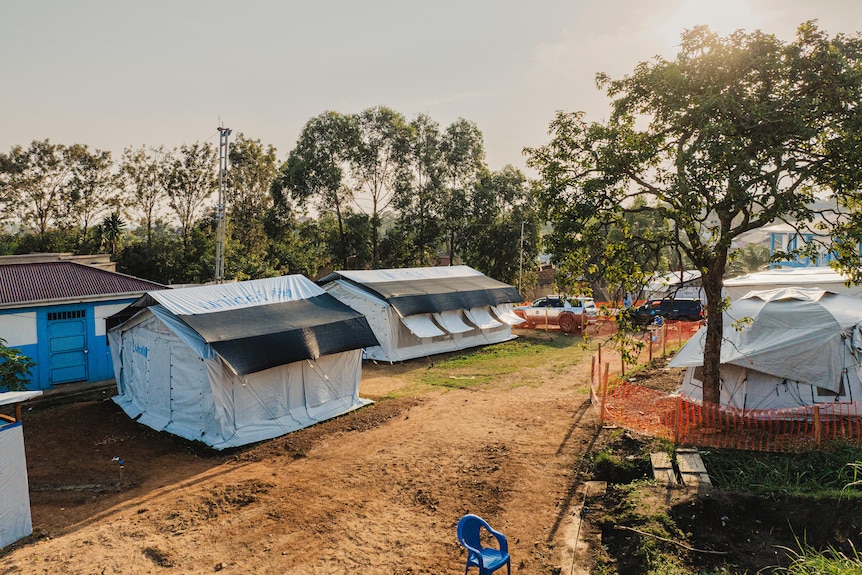 a row of tents stands in a field 