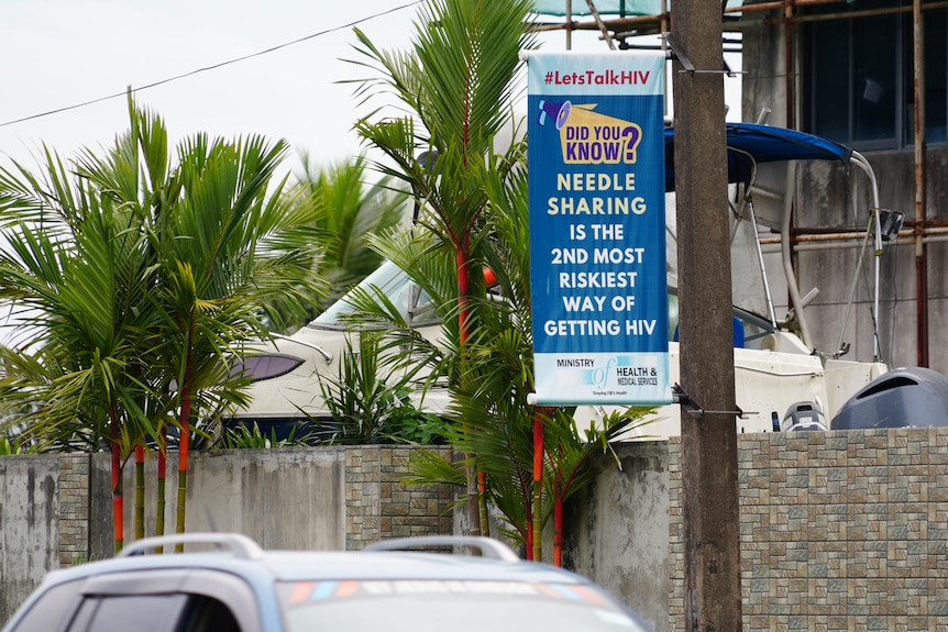 A poster attached to a power pole saying that needle sharing leads to HIV infection.