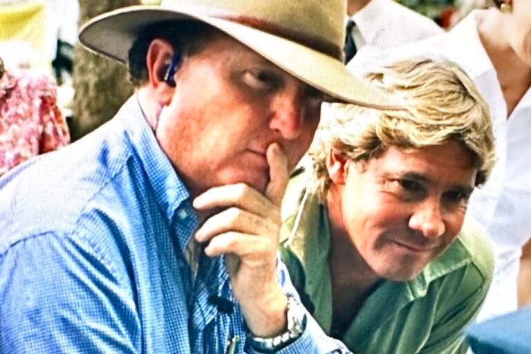 Man in hat and steve irwin in khaki looking at camera gear