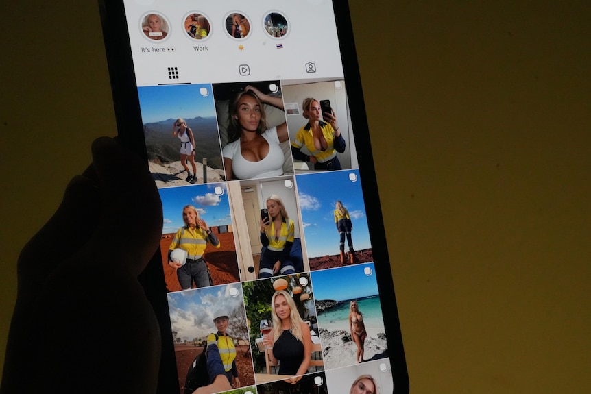 A photo in a dark room with a yellow wash in the background of a hand holding a phone showing bindi