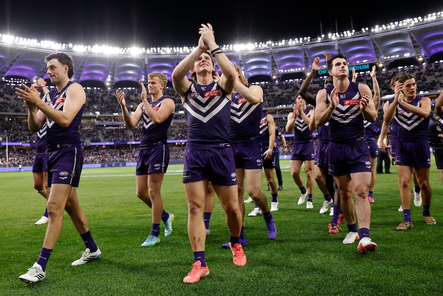 Footballers clap to supporters as they walk off