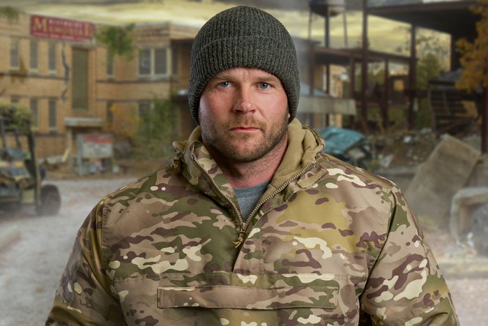 apocalypse-channel-4 (1) A man wearing a camo jacket and grey beanie, smiling slightly.