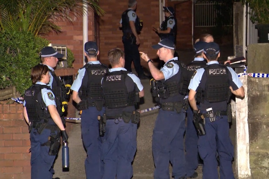 A group of police officers outside a block of flats.