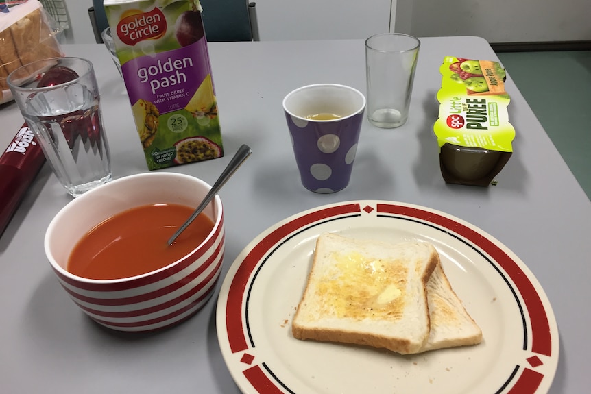 A plate with buttered white toast next to a bowl of tomato soup