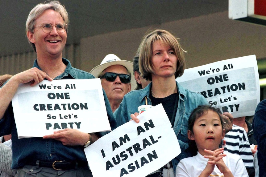 Two men, a woman and a young girl protest with placards saying "I am Austral-asian" and "We're all one creation".