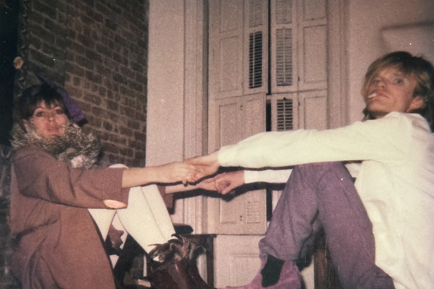 Divinyls vocalist Chrissy Amphlett and guitarist Mark McEntee sit down holding hands.