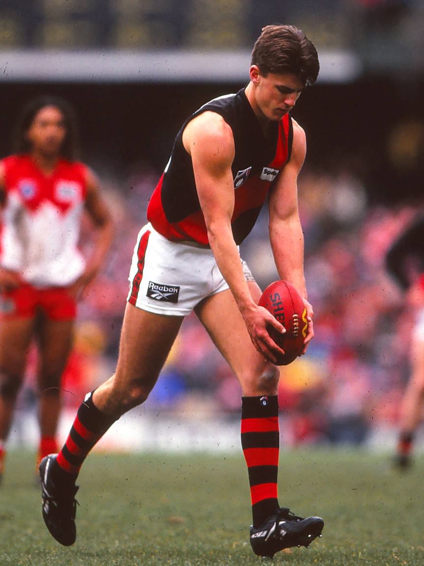 Essendon's Matthew Lloyd looks down at the ball as he runs in to kick against Sydney.