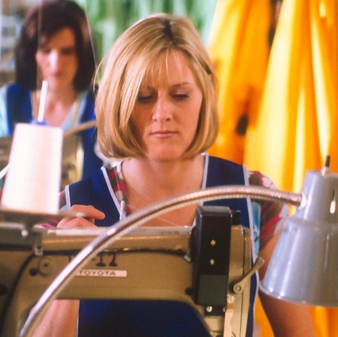 woman sewing in a garment factory with yellow fabric in the background woman sewing in a garment factory with yellow fabric in the background