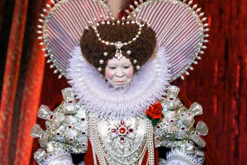 Whoopi Goldberg appears as Queen Elizabeth the First, in an ornate embroidered white costume.
