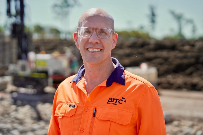 Grant wears glasses and an orange high-vis shirt with an "ARRC" logo.