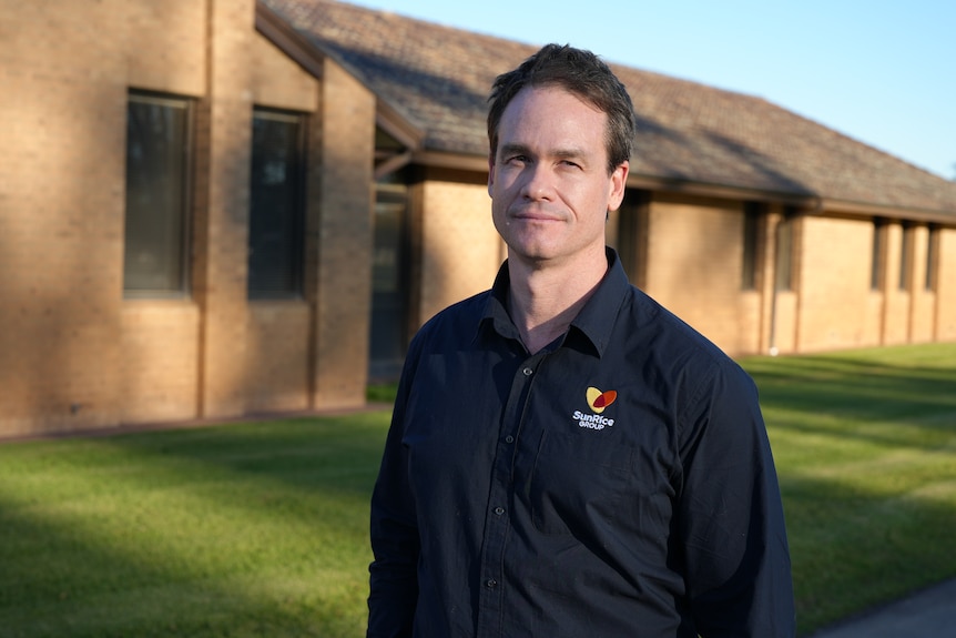 A man (Paul Serra) wearing a navy shirt looks at the camera with a serious expression.
