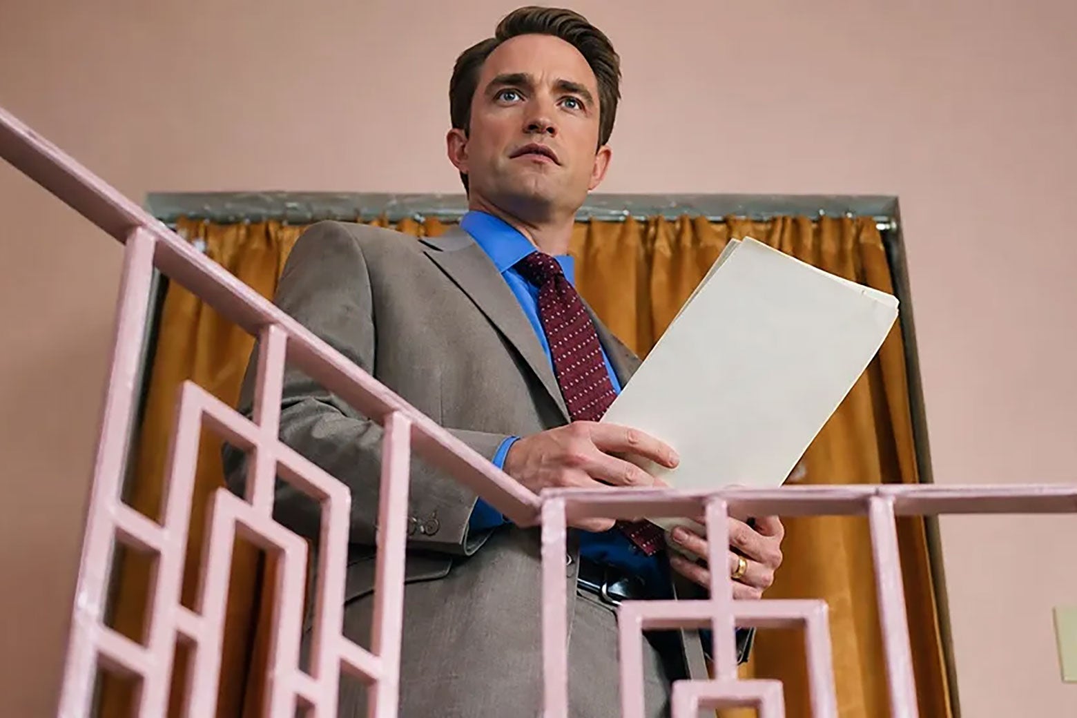 A man with slicked-back hair, a red tie, and a blue suit.