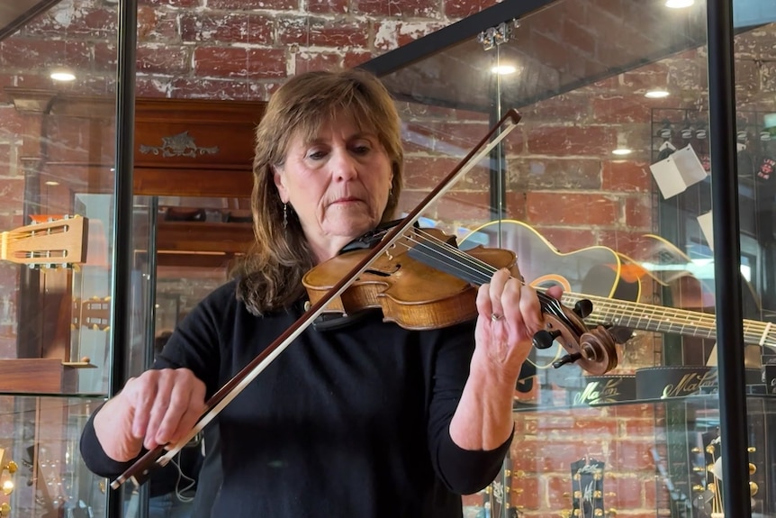 Image of a woman with brown hair playing a violin.
