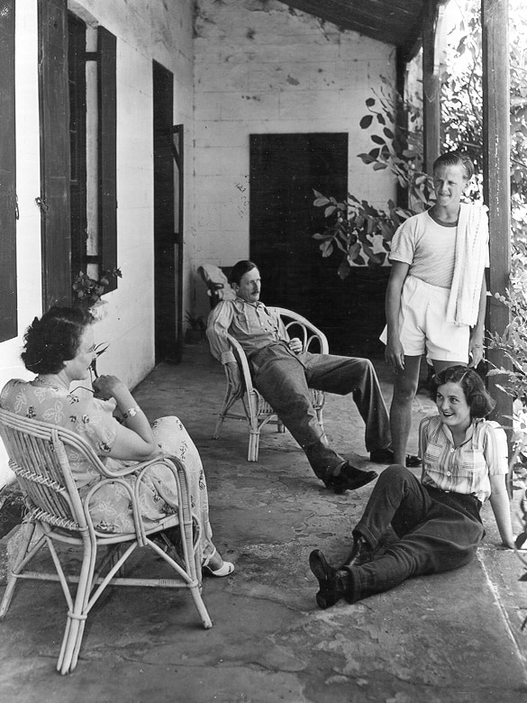 A black and white photograph from the 1940s or 1950s showing a group of voice actors relaxing on a house verandah