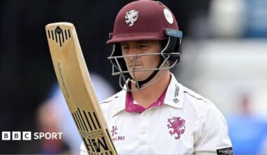 Tom Abell, wearing a white shirt and claret helmet, looks at his bat