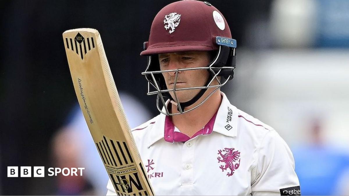 Tom Abell, wearing a white shirt and claret helmet, looks at his bat