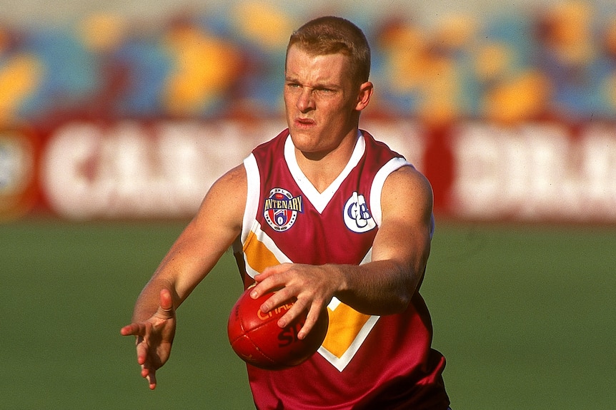 Michael Voss prepares to kick a football with ball in hand