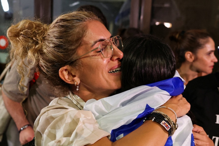Two women embrace at an airport.