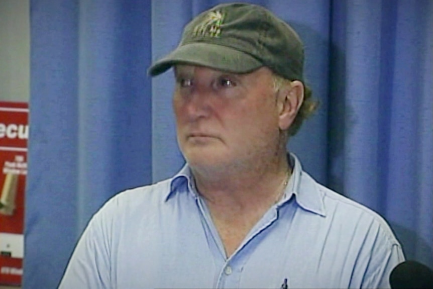 Man looking sad in front of blue curtain