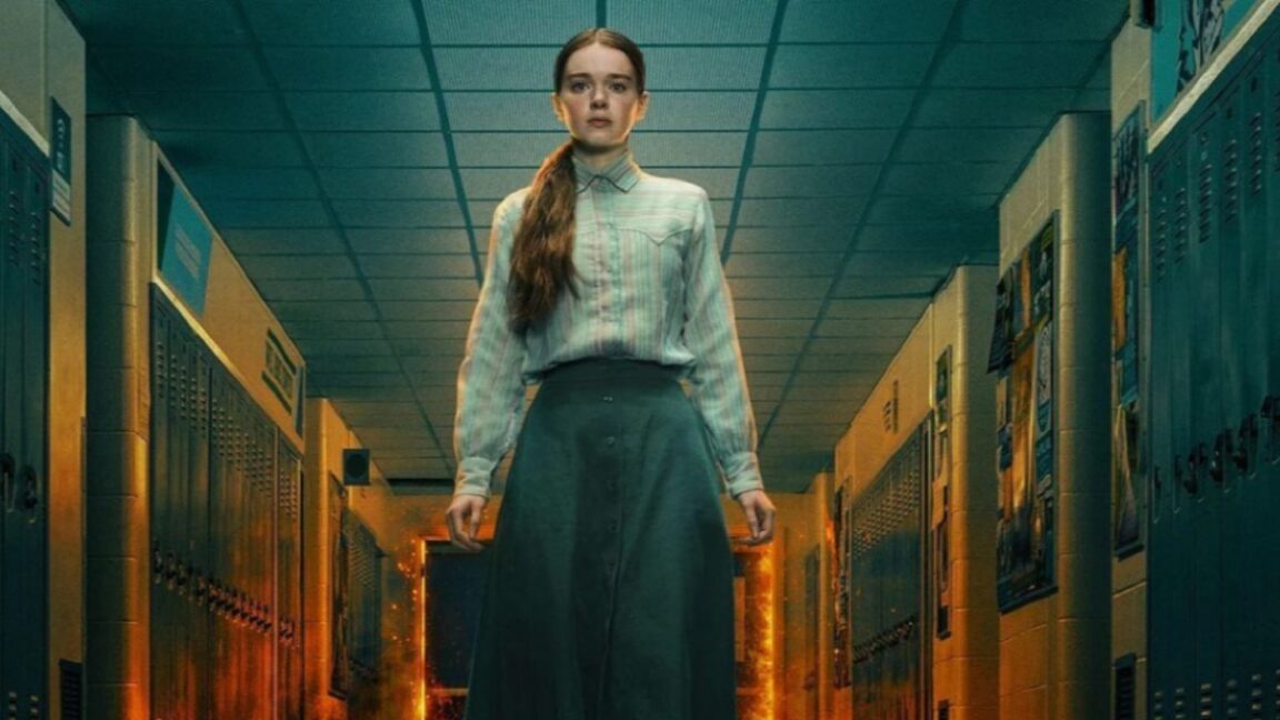 young girl in simple skirt and blouse standing in high school hallway as flames billow behind her