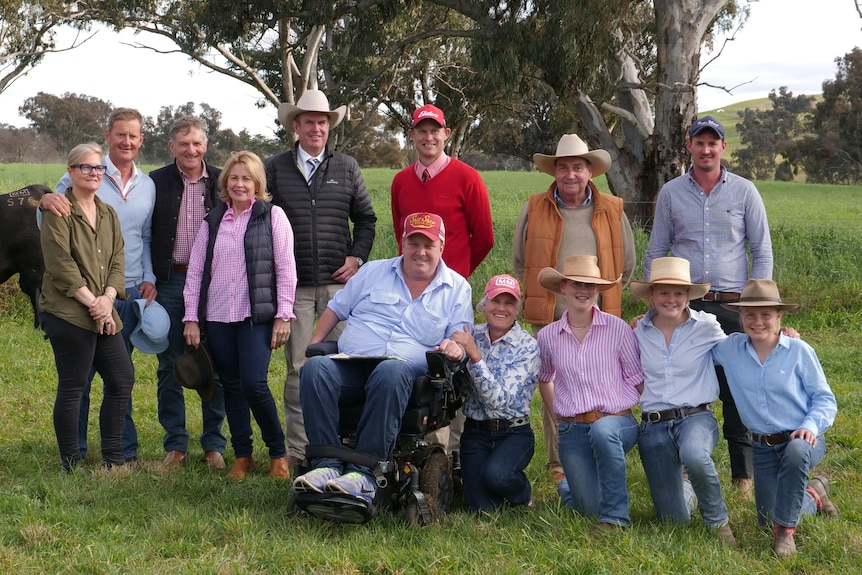 A dozen people standing in front of a black angus bull