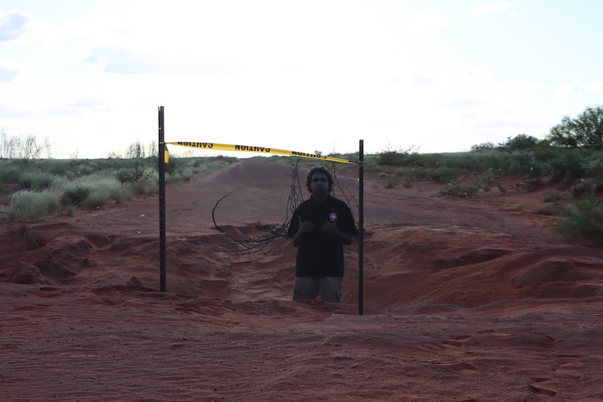A man gives a double thumbs up from a hole in the middle of the road.