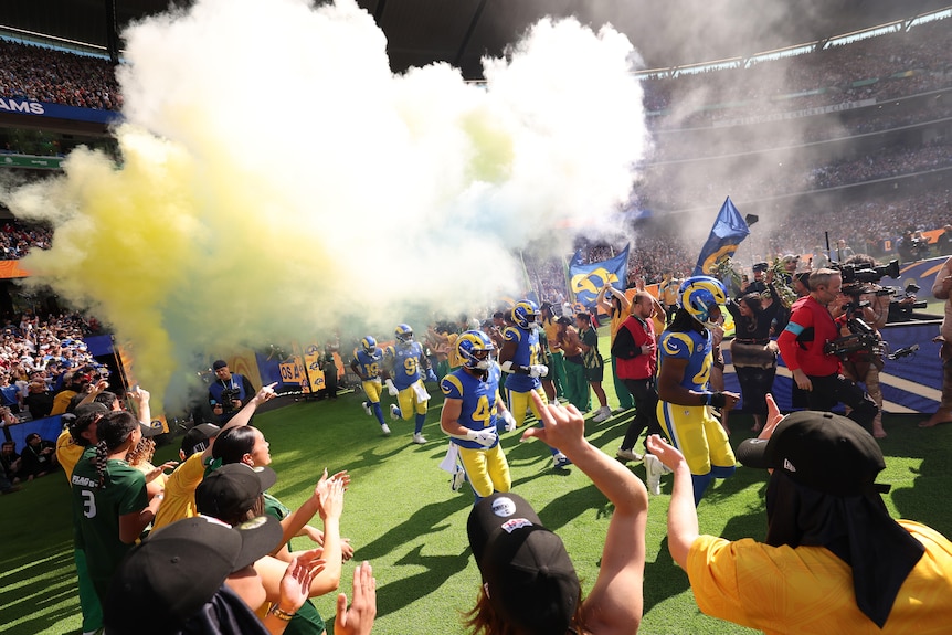 The LA Rams players run out onto ground amid blue and gold smoke