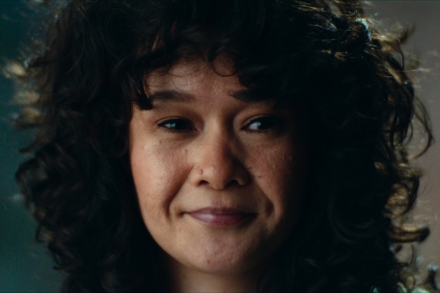 An Asian woman with curly brown hair grinning
