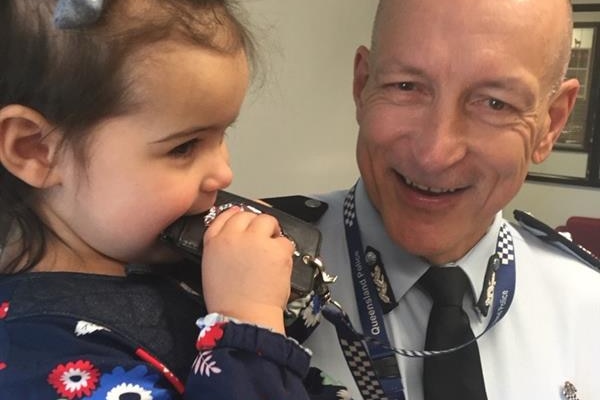 A middle aged man in a police uniform with a young girl