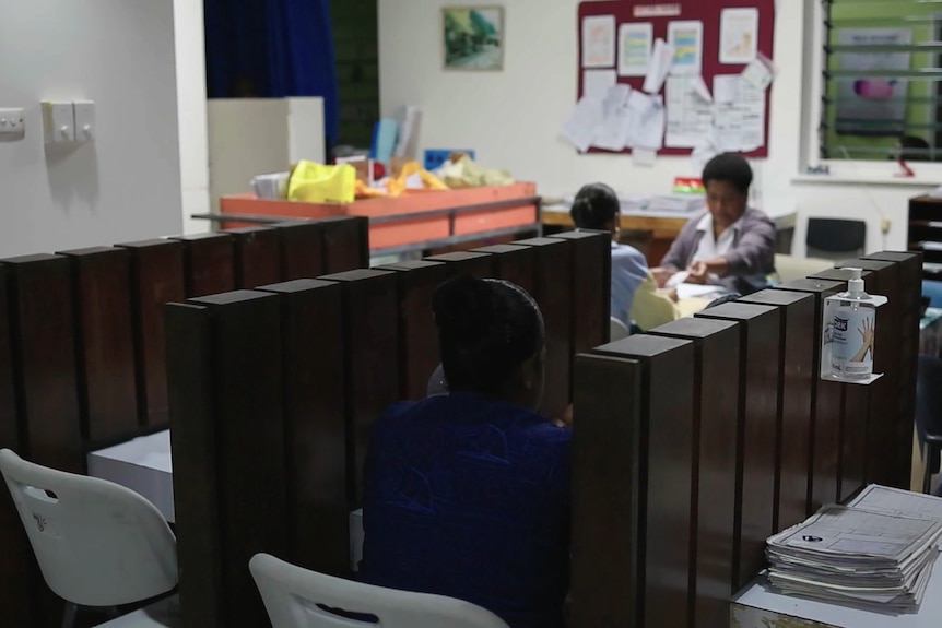 A woman sitting at a counselling booth in a hospital.